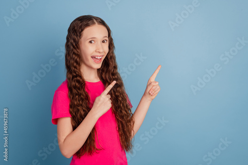 Portrait of charming announcer small lady direct forefingers empty space on blue background