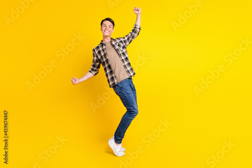 Photo of astonished positive guy celebrate victory wear plaid shirt jeans shoes isolated yellow color background © deagreez