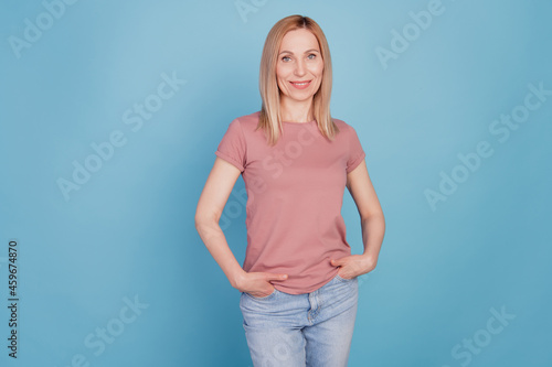 Photo of cheerful positive cute nice young woman hands in pocket confident isolated blue color background © Tetiana