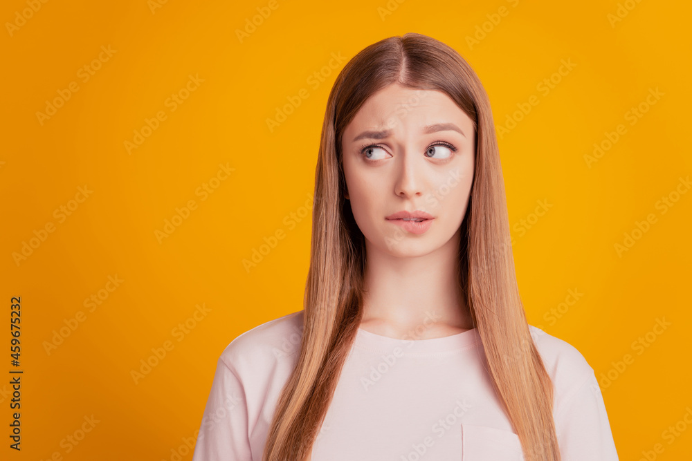Portrait of worried troubled lady bite lip look side empty space think on yellow background Portrait of worried troubled lady bite lip look side empty space think on yellow background