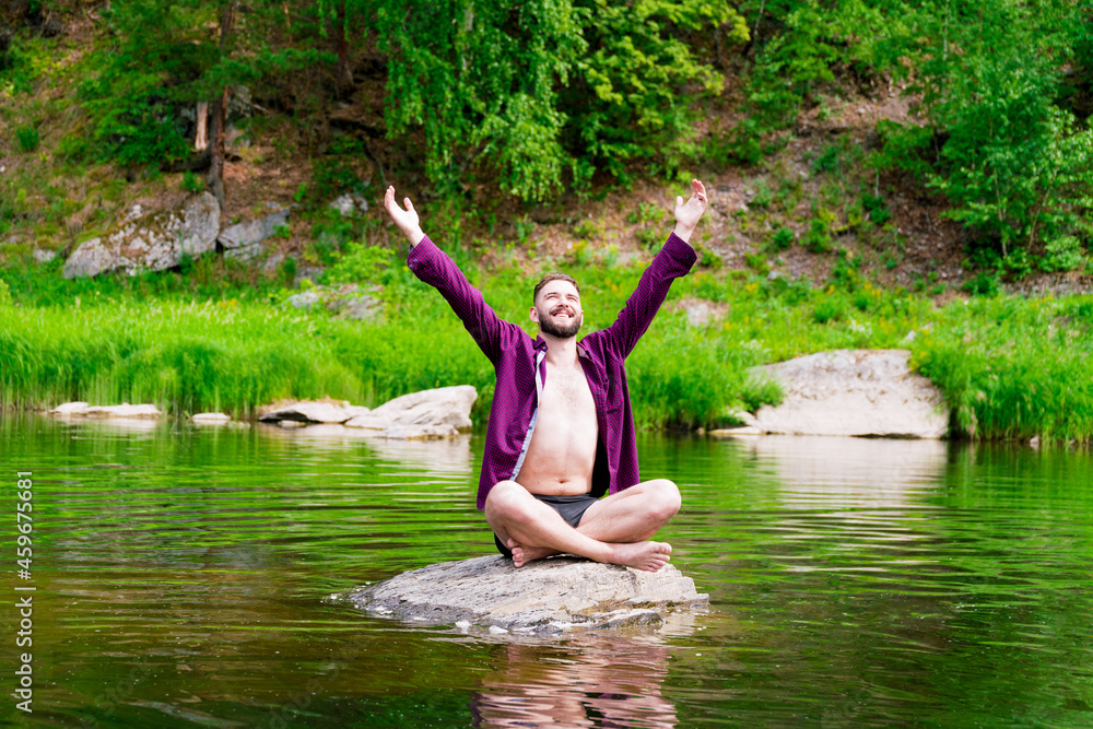 Meditation and peace. A man meditates in the lotus position, sitting on a stone in the middle of a mountain river.. Meditation and peace. A man meditates in the lotus position, sitting on a stone in the middle of a mountain river..