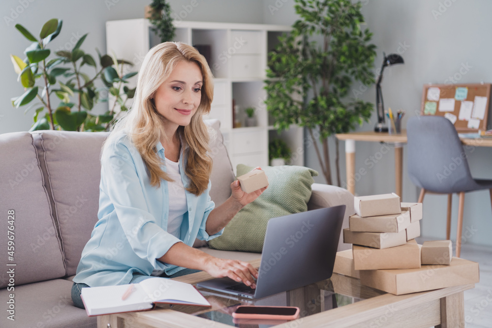 Photo portrait woman blonde hair sitting on sofa using laptop doing unpacking carton boxes Photo portrait woman blonde hair sitting on sofa using laptop doing unpacking carton boxes