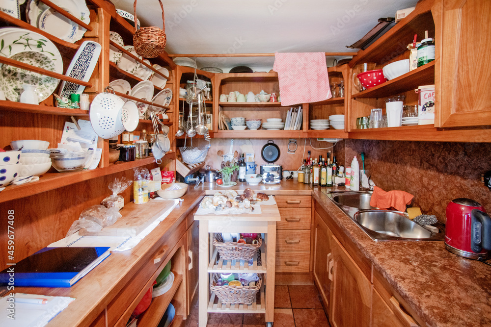 Small kitchen with shelves of dishes and various kitchen
