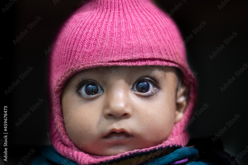 isolated toddler cute facial expression in monkey woolen cape close up shot with black background
