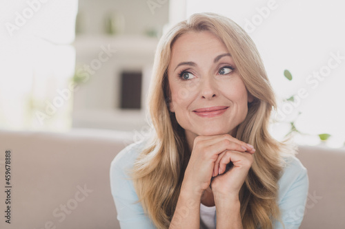 Photo of thoughtful minded lady look side hands chin imagine idea wear blue shirt home apartment indoors