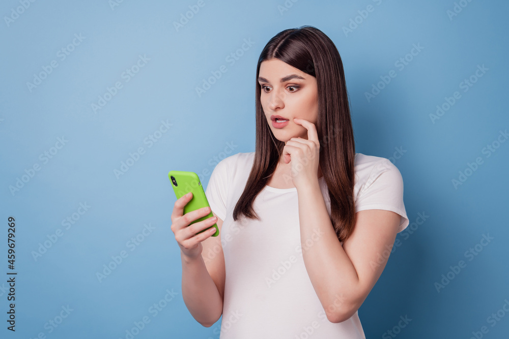Portrait of cute pretty stunning lady hold telephone look screen on blue background Portrait of cute pretty stunning lady hold telephone look screen on blue background