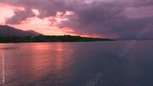 Beautiful sunset reflecting on the sea with a man returning home in his canoe after fishing. photo