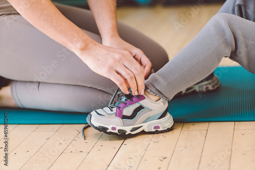 Mom helps daughter to tie her shoelaces. Preparing