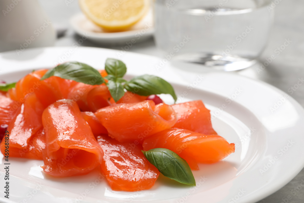 Salmon carpaccio with basil on plate, closeup