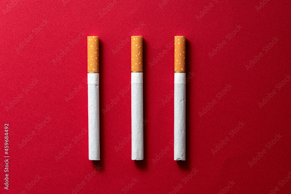 Three pieces cigarette evenly spaced on a dark red Three pieces cigarette evenly spaced on a dark red