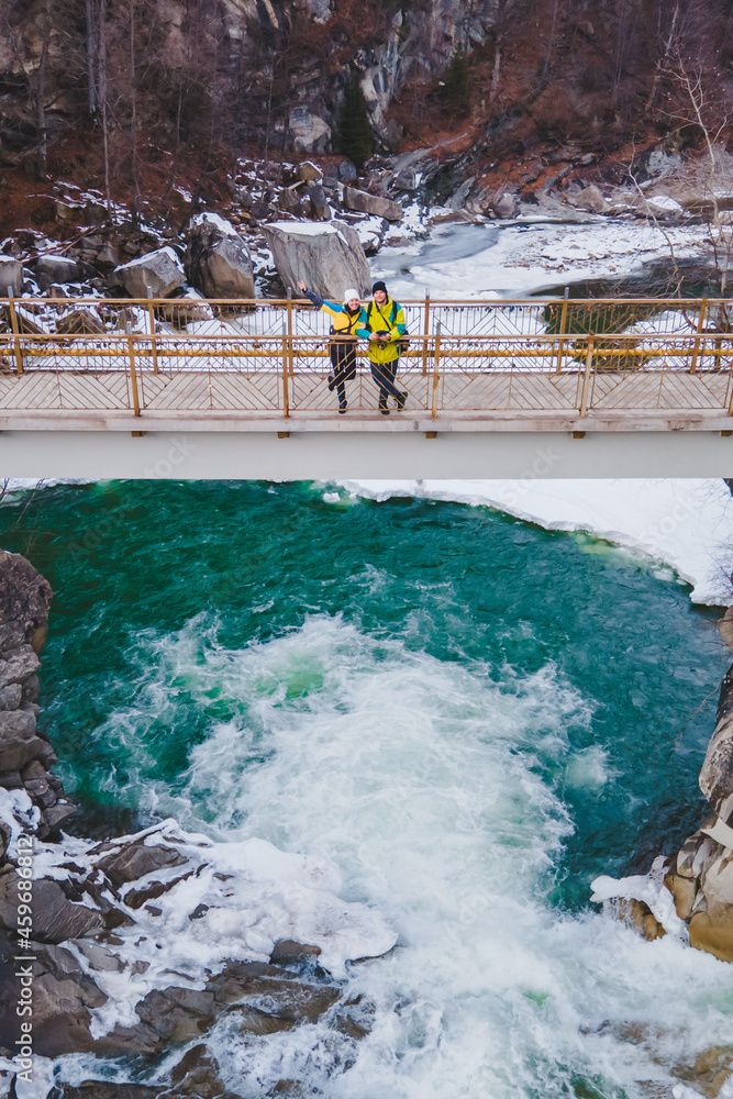 couple travelers on the bridge across waterfall