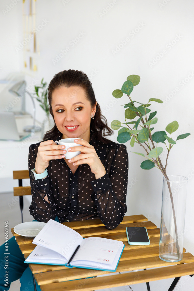 Portrait of beautiful woman in black blouse, with cup. Brunette holds white mug in her hands, drinks coffee or tea. Female in business Portrait of beautiful woman in black blouse, with cup. Brunette holds white mug in her hands, drinks coffee or tea. Female in business