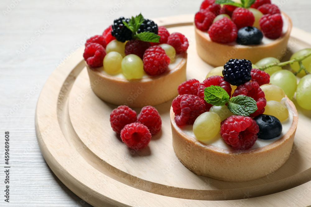 Delicious tartlets with berries on light wooden table, closeup Delicious tartlets with berries on light wooden table, closeup
