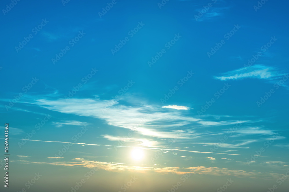 Sunset in sky with blue clouds and big shining sun