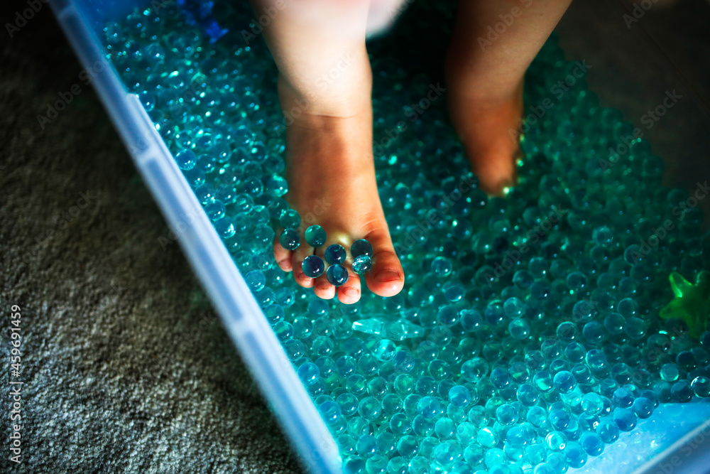 Baby play sensory hydrogel box, kid feet play with blue water