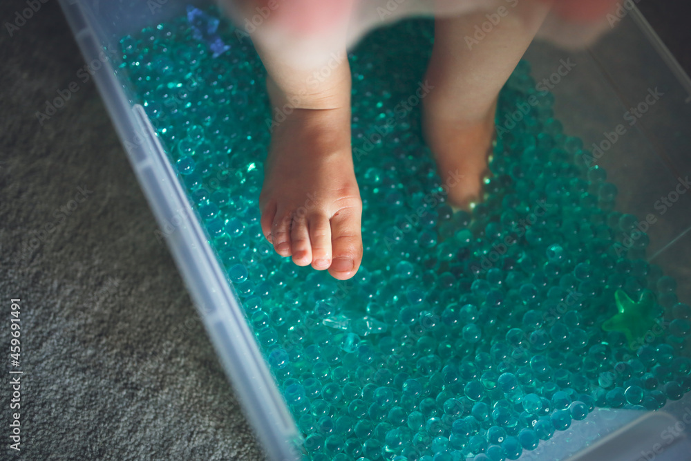 Baby play sensory hydrogel box, kid feet play with blue water beads ...