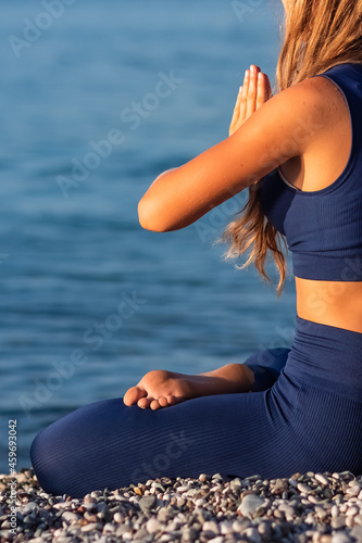 Young girl sitting in Lotus pose on the beach at sunset.