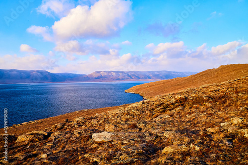 Nature landscape with golden field, wather, hills and blue sky with white clouds in a day or a evening photo