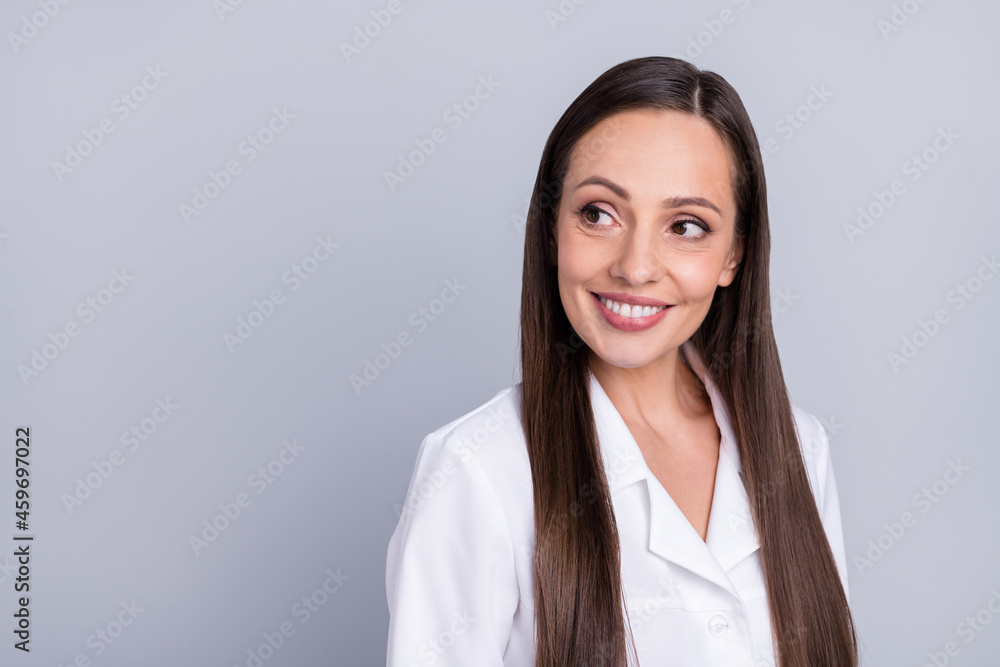 Photo of mature attractive woman doctor happy positive smile curious look empty space isolated over grey color background Photo of mature attractive woman doctor happy positive smile curious look empty space isolated over grey color background