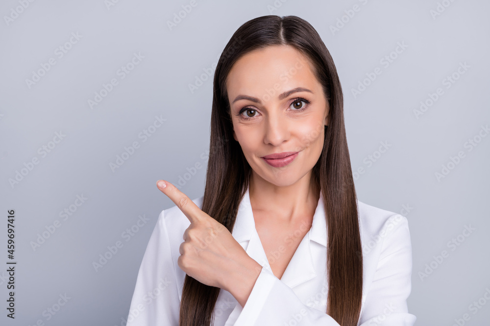 Photo of pretty sweet lady doctor wear white formal coat smiling pointing finger empty space isolated grey color background Photo of pretty sweet lady doctor wear white formal coat smiling pointing finger empty space isolated grey color background