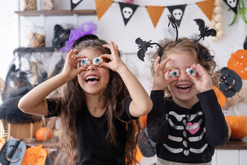 two diverse kids girl in costume of witch, having fun at home in kitchen, celebrating Halloween