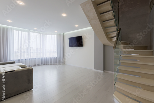 interior of a large living room with gray walls and stairs in a modern style © Liubomir