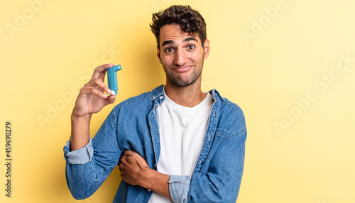 hispanic handsome man shrugging, feeling confused and uncertain. asthma concept photo