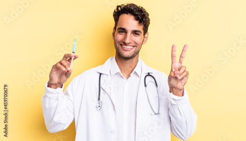 hispanic handsome man smiling and looking happy, gesturing victory or peace physician and srynge concept photo