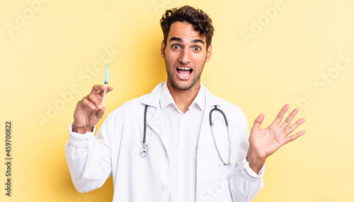 hispanic handsome man feeling happy and astonished at something unbelievable physician and srynge concept photo