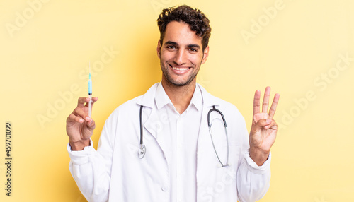 hispanic handsome man smiling and looking friendly, showing number three physician and srynge concept photo