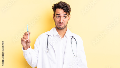 hispanic handsome man looking puzzled and confused physician and srynge concept photo