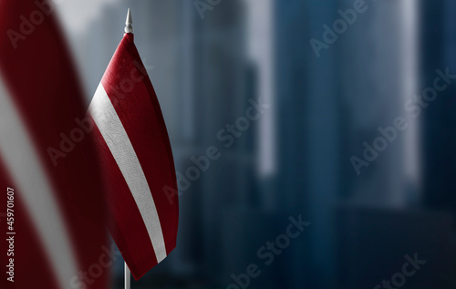 Small flags of Latvia on a blurry background of the city photo