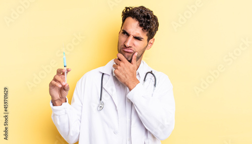 hispanic handsome man thinking, feeling doubtful and confused physician and srynge concept photo