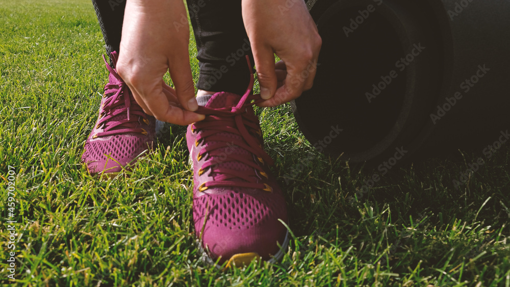 Young woman ties the laces on the pink sneaker. Woman preparing for