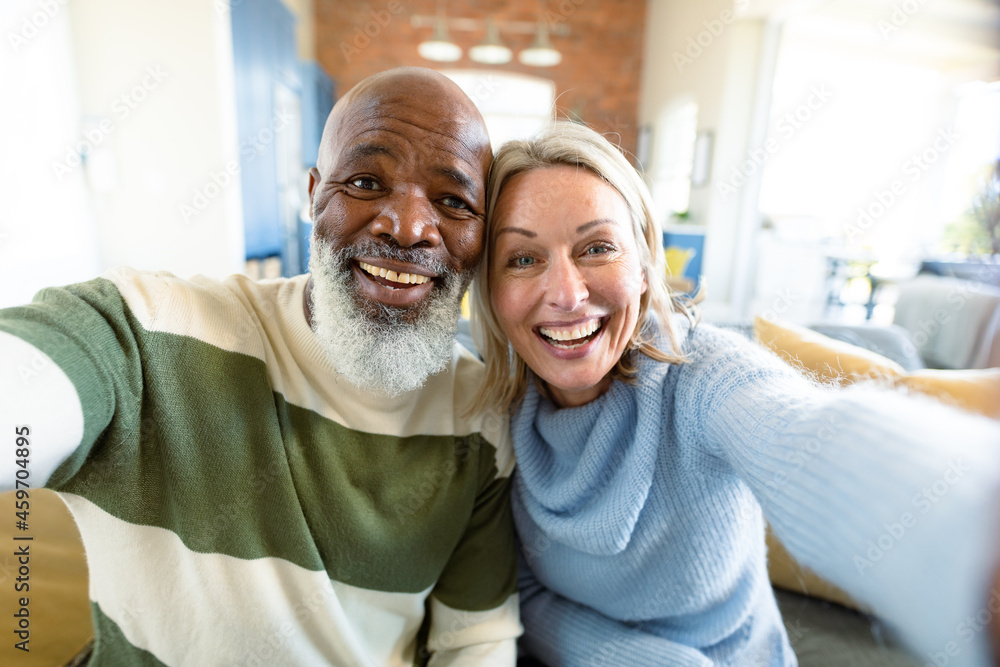 Happy senior diverse couple in living room sitting on sofa, making video call Happy senior diverse couple in living room sitting on sofa, making video call