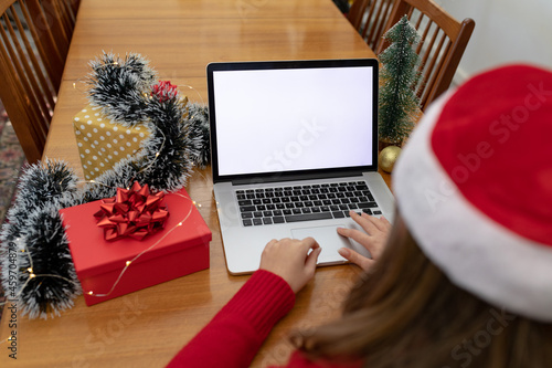 Caucasian woman wearing santa hat having video call on laptop with copy space at christmas time