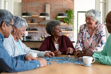Group of diverse senior male and female friends doing puzzles at home