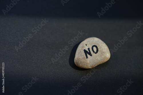 Pebble stone with text NO on black table
