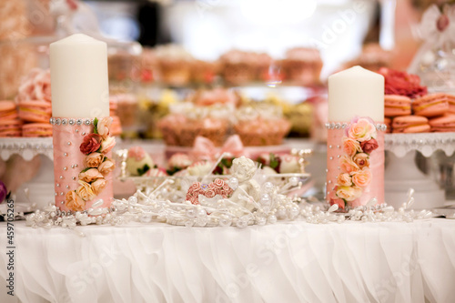 Delicious desserts at the wedding candy bar in the buffet area  candles decorated with rosebuds and ribbons