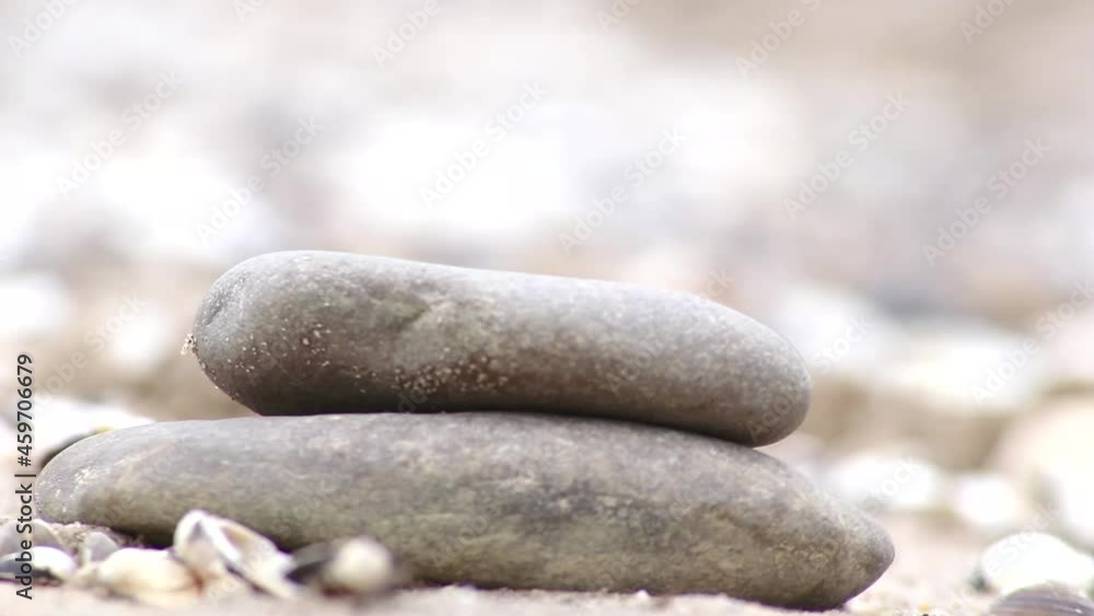 European male hand building stone stack at a river shore in tranquil atmosphere with calm movement of fingers and pebbles shows zen like harmony and relaxation in nature and coast side stone pyramid European male hand building stone stack at a river shore in tranquil atmosphere with calm movement of fingers and pebbles shows zen like harmony and relaxation in nature and coast side stone pyramid