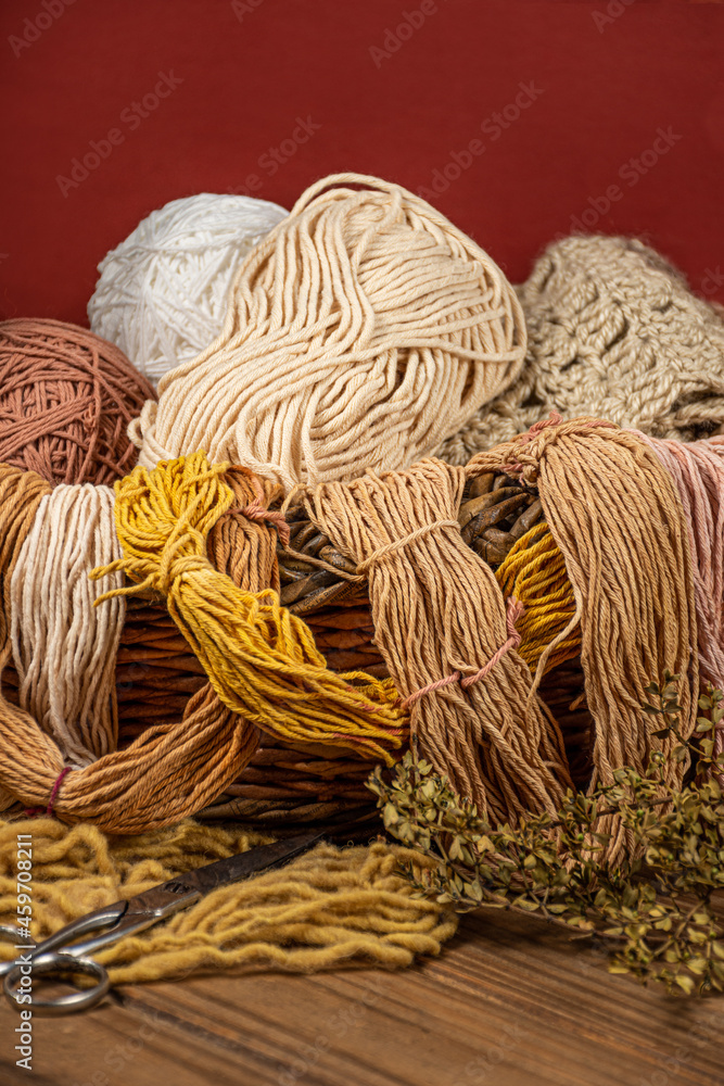 Cesta con madejas de lanas de colores variados.