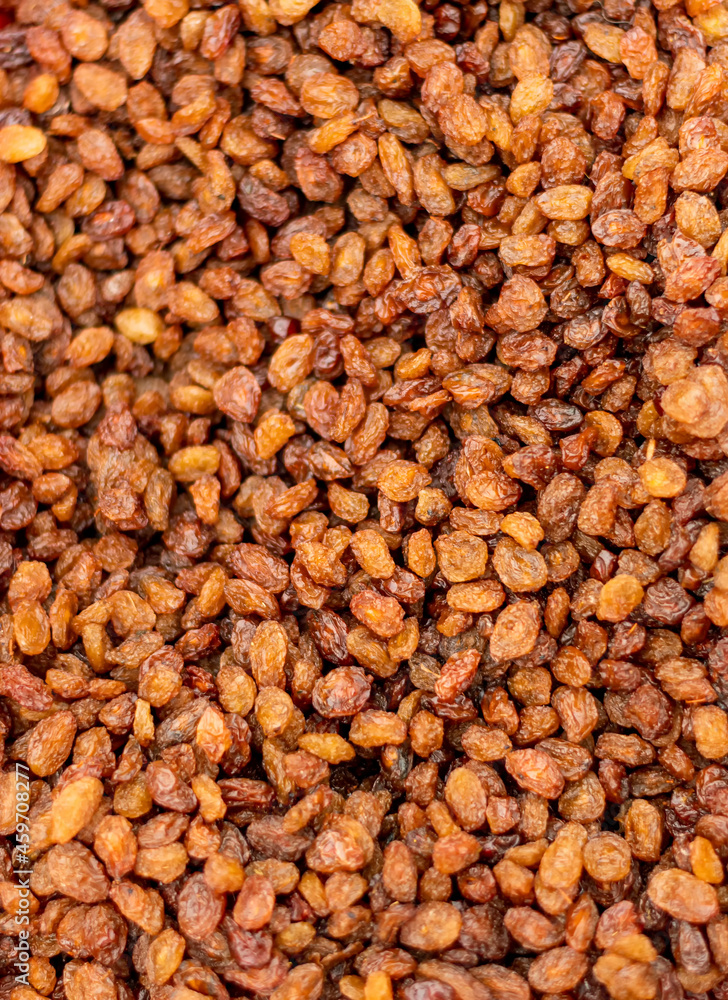Dark grains of raisins (dried grapes) lie on the counter and form an abstract texture. Dark grains of raisins (dried grapes) lie on the counter and form an abstract texture.