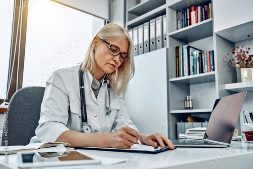 Female doctor writing prescription in a bright office.