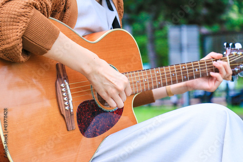 女の子がアコースティックギターを弾いている風景