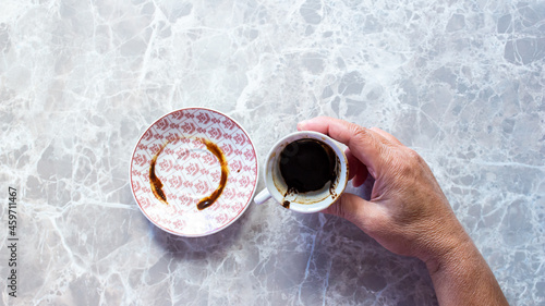 Woman hand holding Turkish coffee cup for fortune telling.