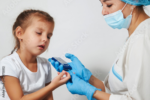 Young nurse doctor measuring blood sugar level of girl