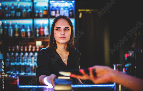 Contactless mobile payment. Payment terminal and smartphone in hands in bar