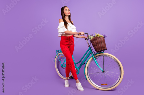 Photo of cheerful dreamy inspired lady drive bike deliver flowers wear white blouse isolated violet color background © deagreez