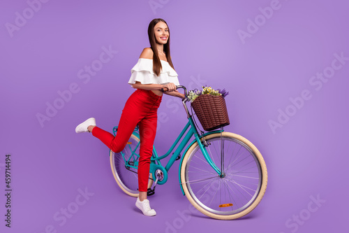 Photo of carefree dream lady ride bike stand tiptoe wear white blouse trousers sneakers isolated violet color background © deagreez