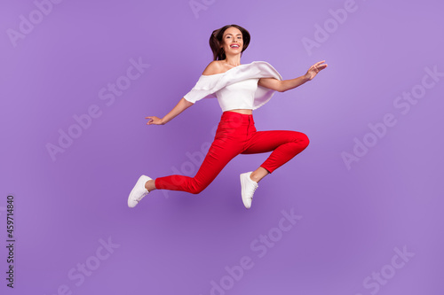 Photo of lovely cheerful lady jump enjoy flight go move wear white blouse pants isolated violet color background